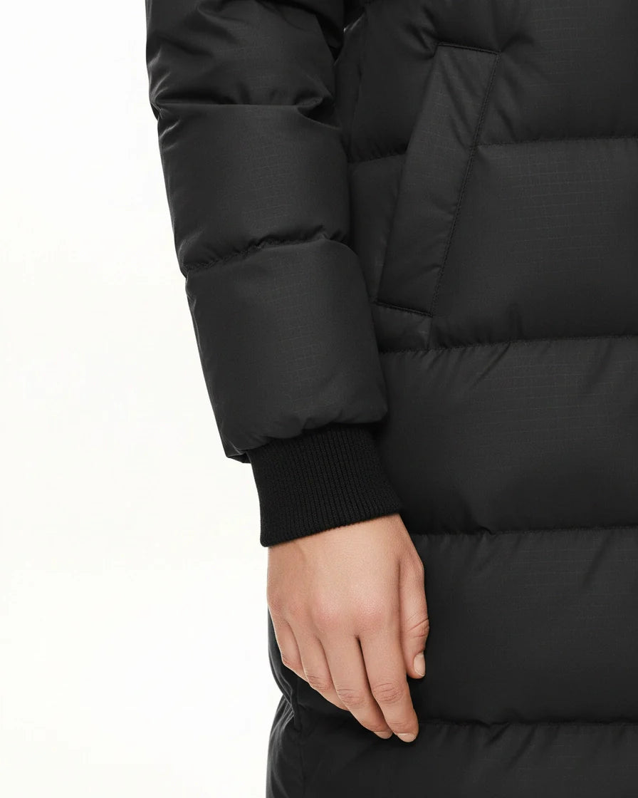 A black long-sleeve midi puffer coat featuring horizontal quilting, a large drawstring hood with orange accents, and a front zipper. - 7