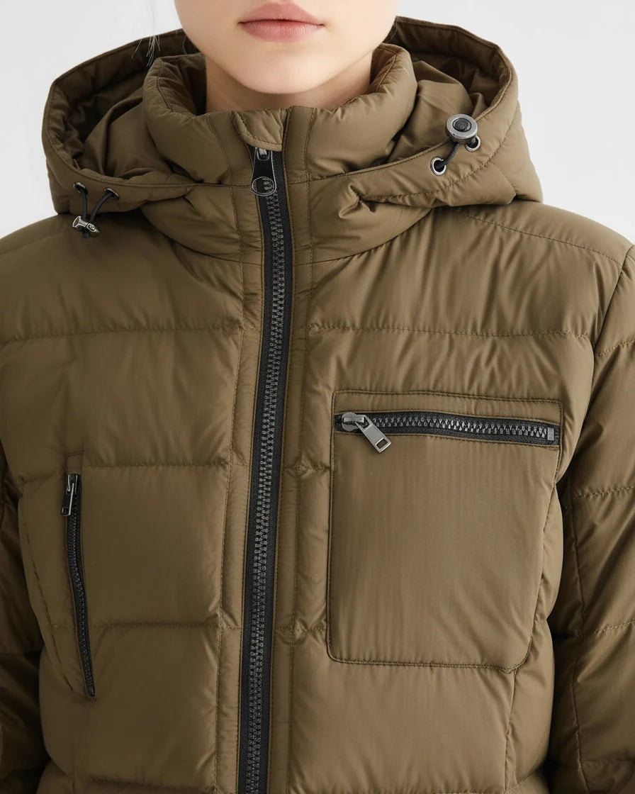Mid-length olive green quilted puffer coat with a hood and black zipper details on a model. - 6