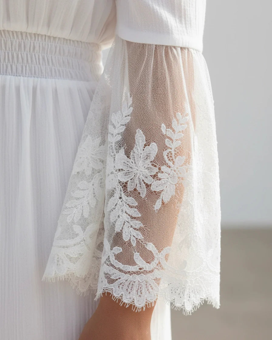 A flowing off-the-shoulder maxi dress in white with lace-trimmed bell sleeves and a tiered skirt. - 5