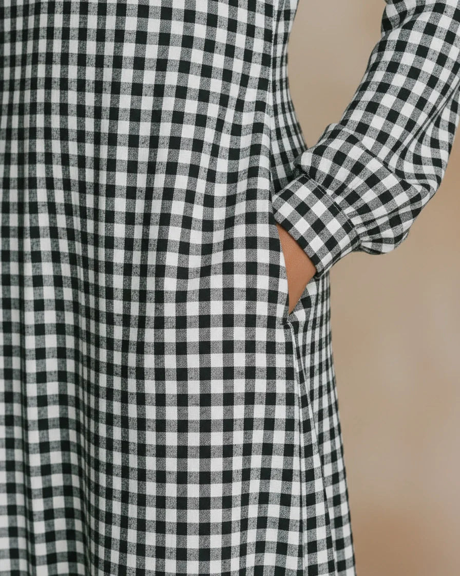 Front view of a woman wearing a black and white gingham plaid maxi dress with long sleeves and a split V-neckline. - 4