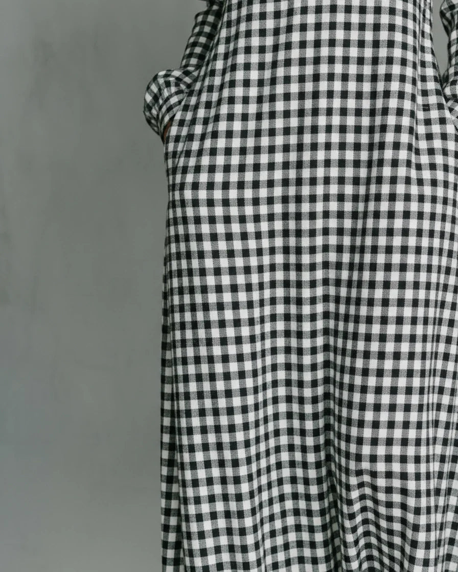 Front view of a woman wearing a black and white gingham plaid maxi dress with long sleeves and a split V-neckline. - 5