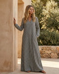Front view of a woman wearing a black and white gingham plaid maxi dress with long sleeves and a split V-neckline.