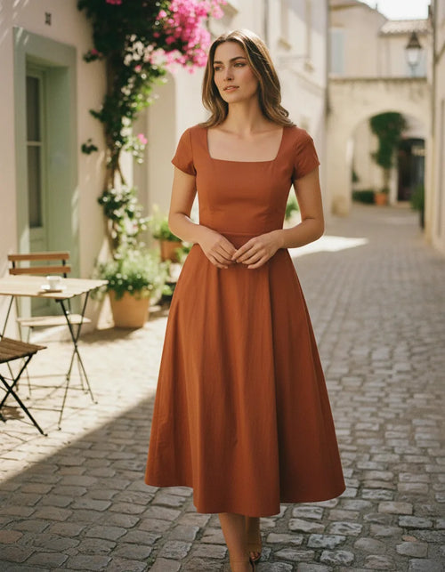 Woman wearing a terracotta cotton poplin midi dress in a Mediterranean summer setting