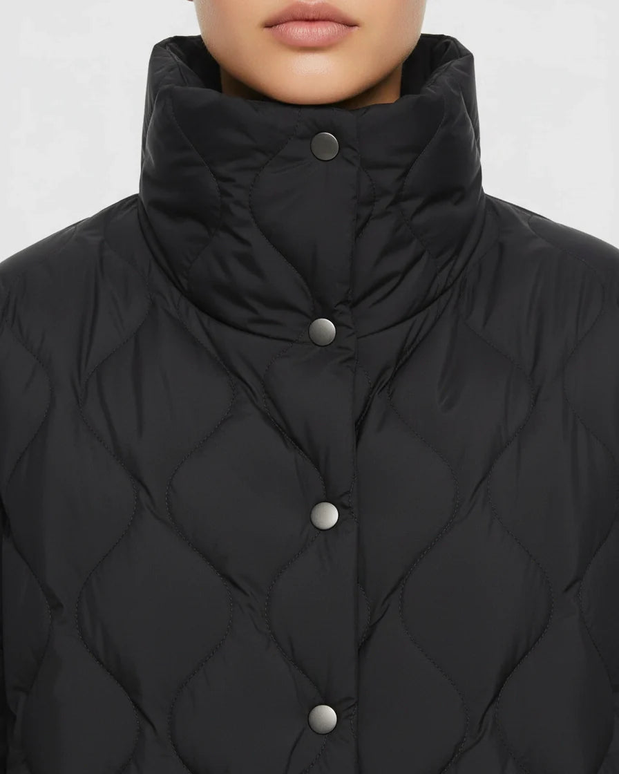 Black diamond quilted puffer jacket with a high stand collar and snap closures on a model. - 6