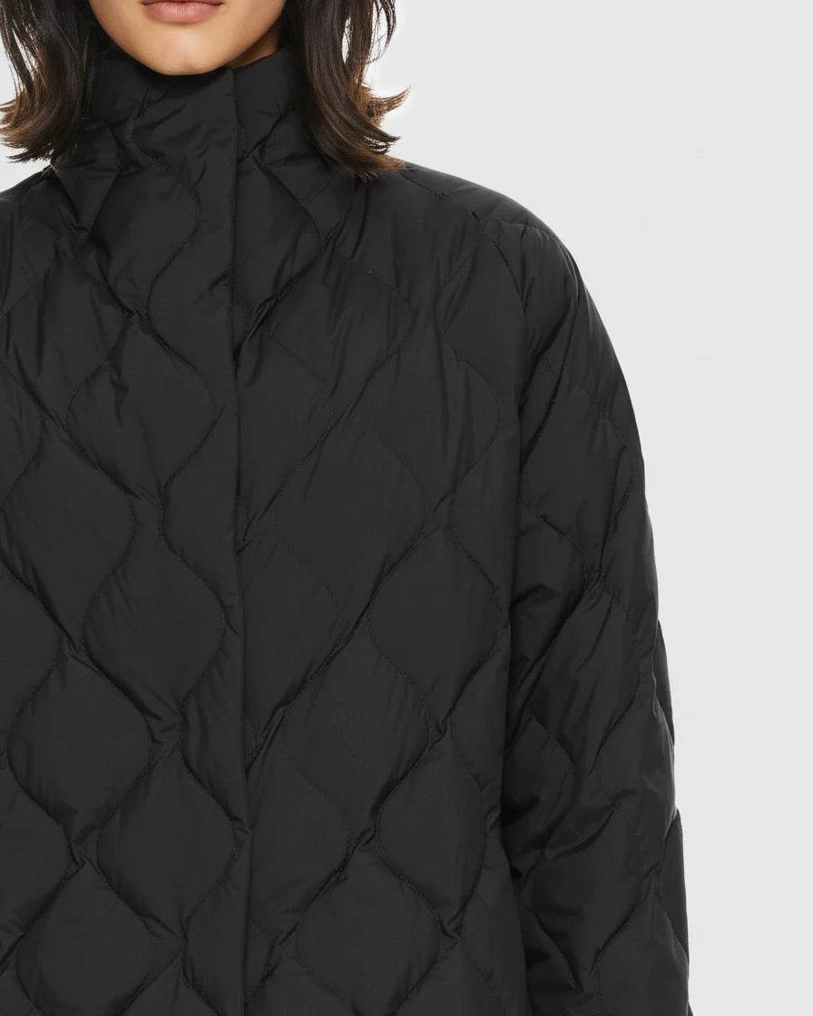 Black diamond quilted puffer jacket with a high stand collar and snap closures on a model. - 8