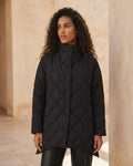 Black diamond quilted puffer jacket with a high stand collar and snap closures on a model.
