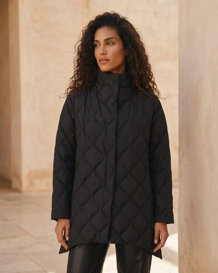Black diamond quilted puffer jacket with a high stand collar and snap closures on a model.