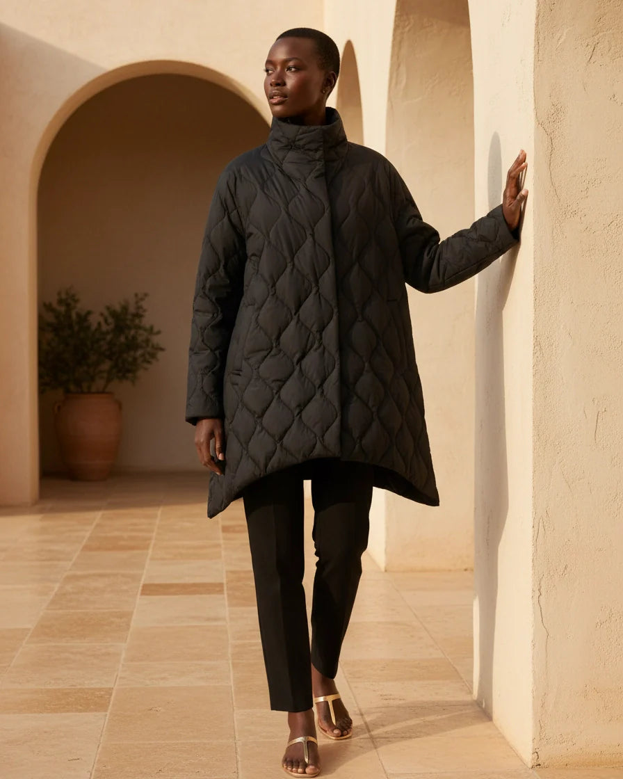 Black diamond quilted puffer jacket with a high stand collar and snap closures on a model. - 2