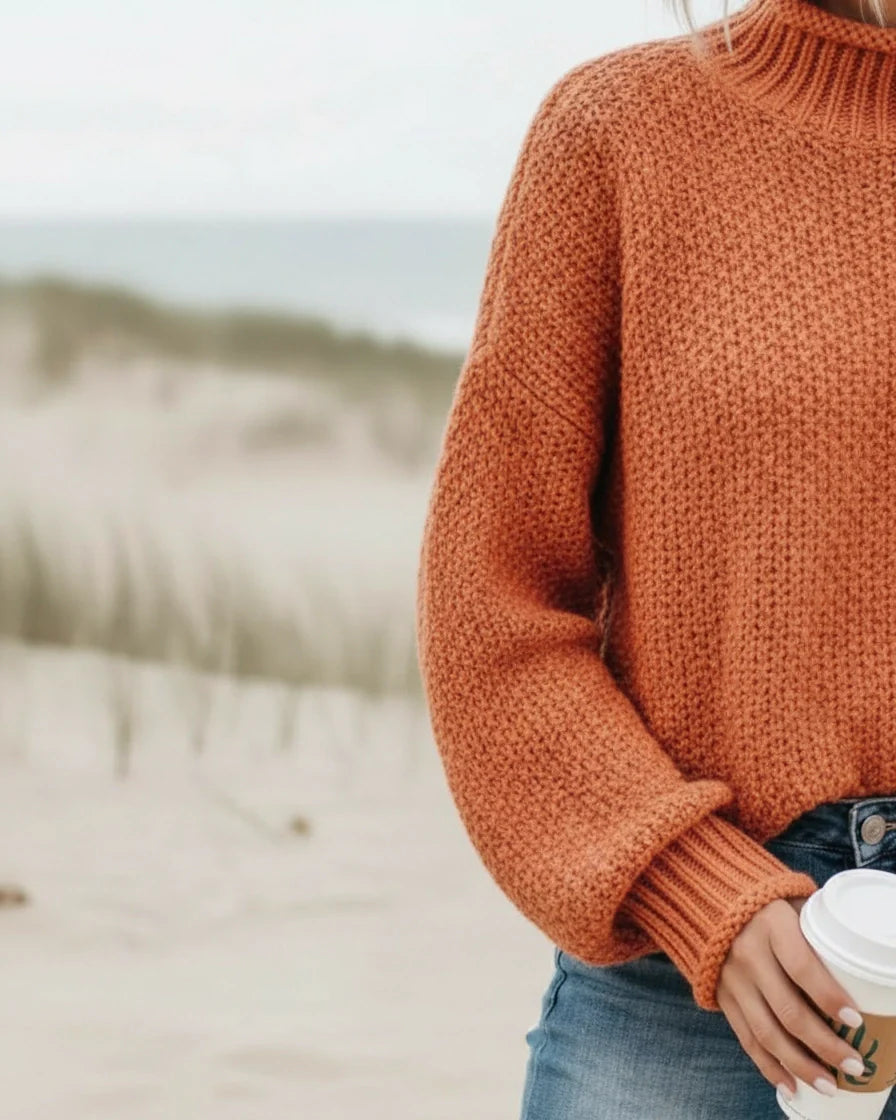 Model wearing a relaxed orange knit sweater with a mock neck and drop shoulders. - 7