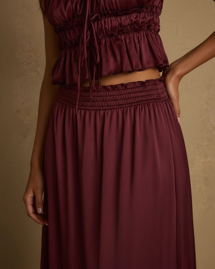 A mulberry burgundy satin two-piece set featuring a ruffled crop top and a tiered maxi skirt. - 3